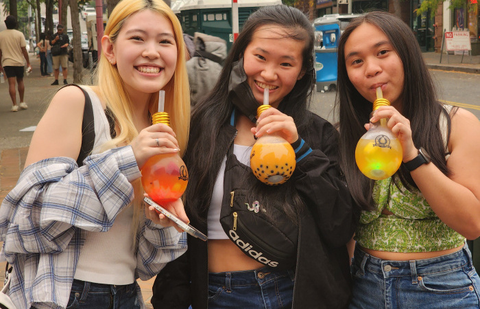 3 friends holding boba in light bulb shaped cups.